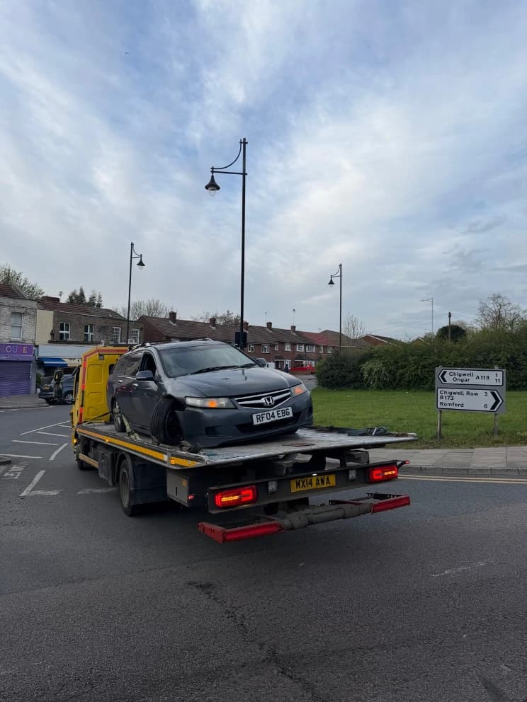 Damaged Honda Accord loaded on a flatbed recovery truck after an accident