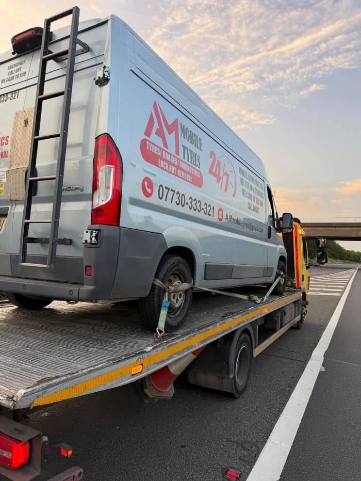 AHS Recovery flatbed truck recovering a breakdown on the motorway at sunset
