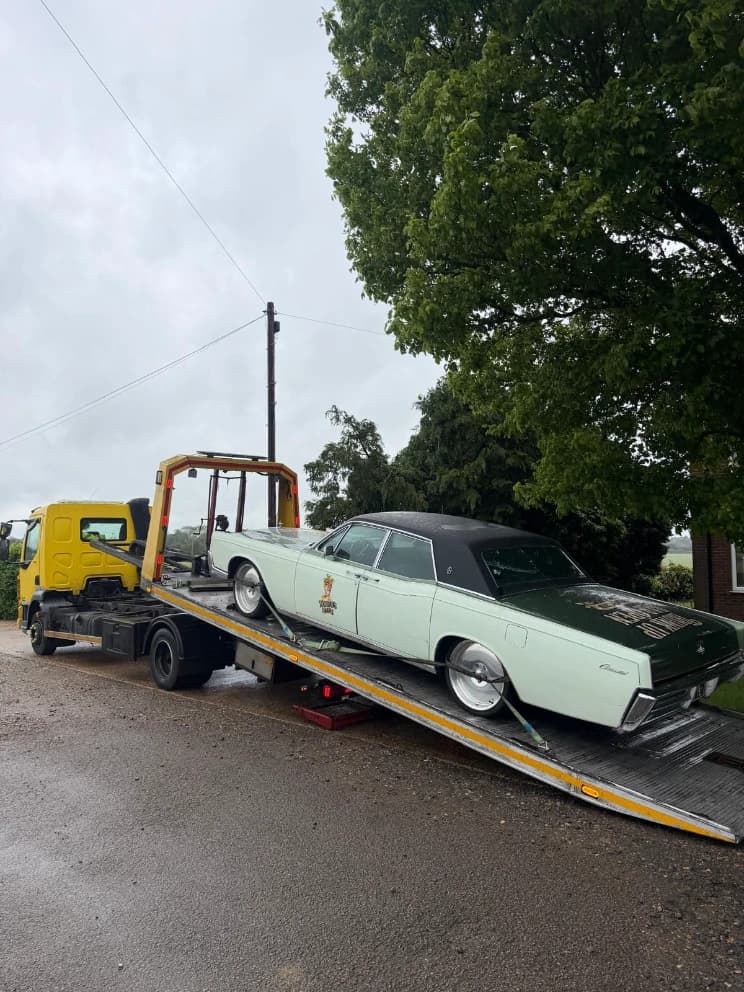 Classic American saloon car loaded on a flatbed recovery truck