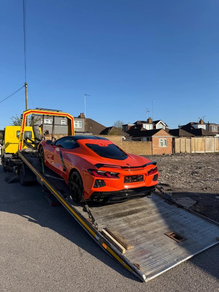 Chevrolet Corvette loaded on a flatbed recovery truck on a residential street