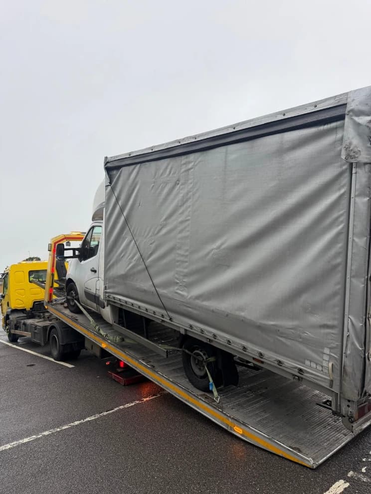 Curtain-side lorry loaded on a flatbed recovery truck