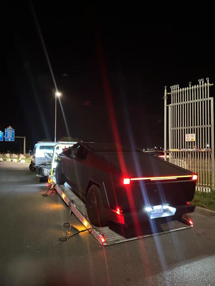 Tesla Cybertruck loaded on a flatbed recovery truck at night