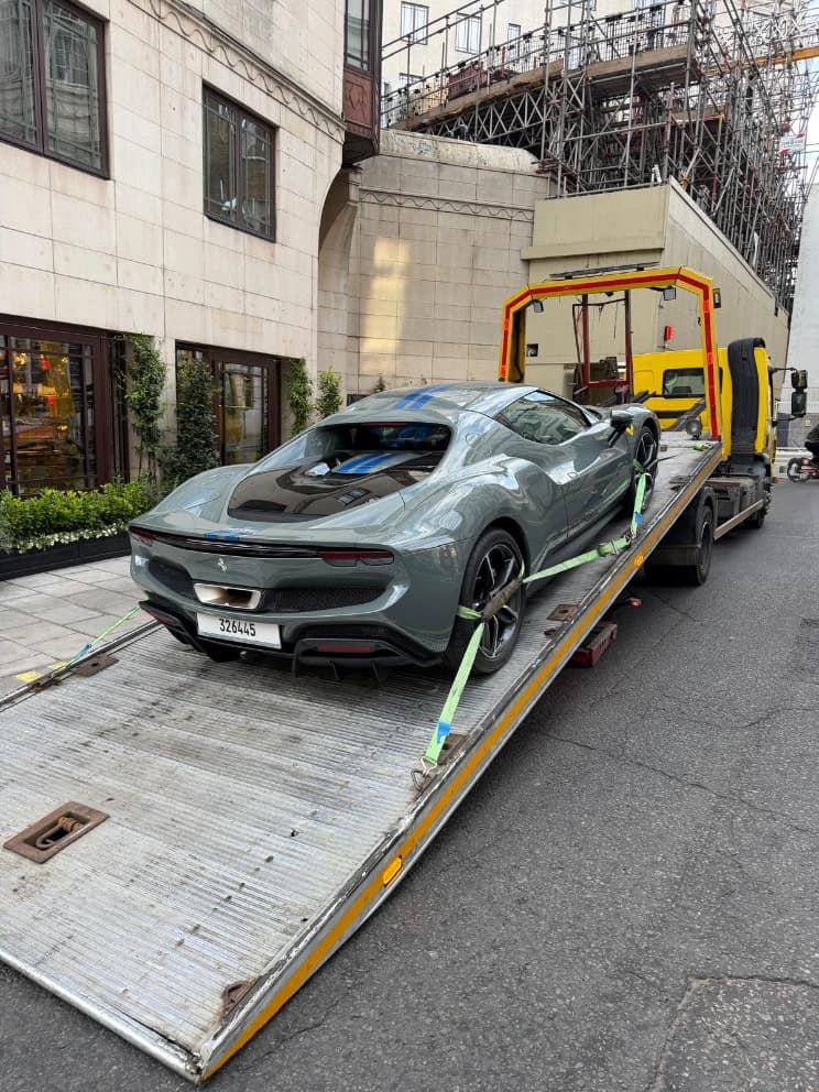 Ferrari Purosangue SUV loaded on a flatbed recovery truck on a city street