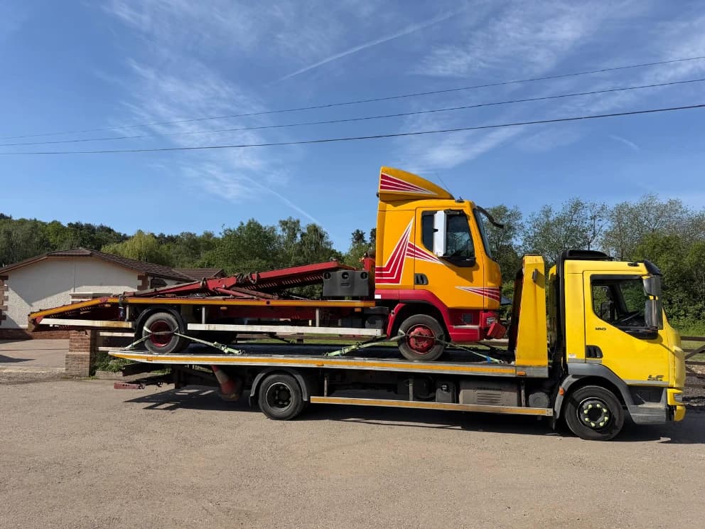 Hookloader truck loaded on a flatbed recovery vehicle