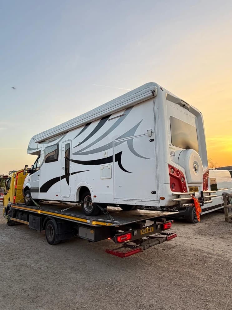 Motorhome loaded on a flatbed recovery truck at sunset