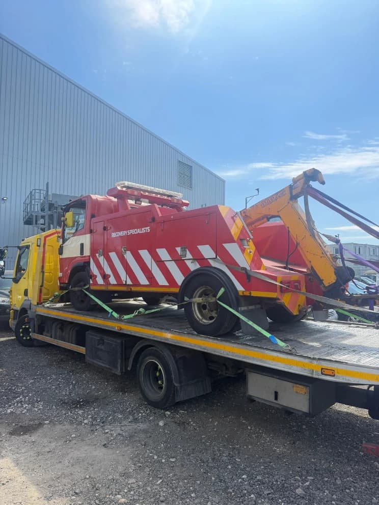 Heavy-duty recovery truck itself being transported on a larger flatbed