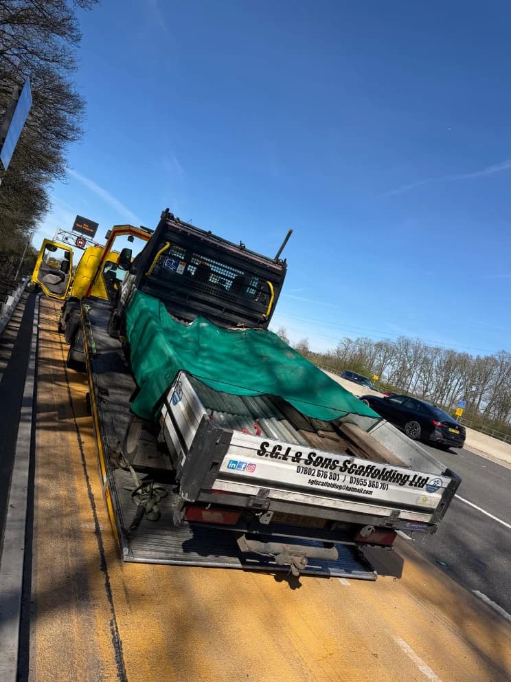 Scaffolding-laden truck loaded on a flatbed recovery vehicle on the motorway