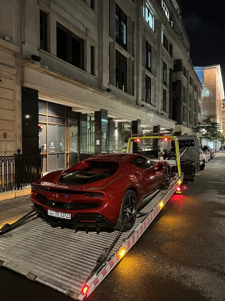 Ferrari sports car loaded on a flatbed recovery truck on a city street at night