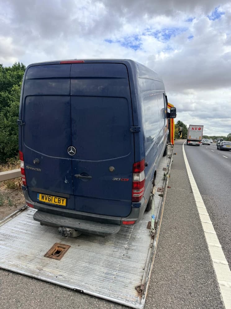 Mercedes Sprinter van loaded on a flatbed recovery truck on the motorway hard shoulder