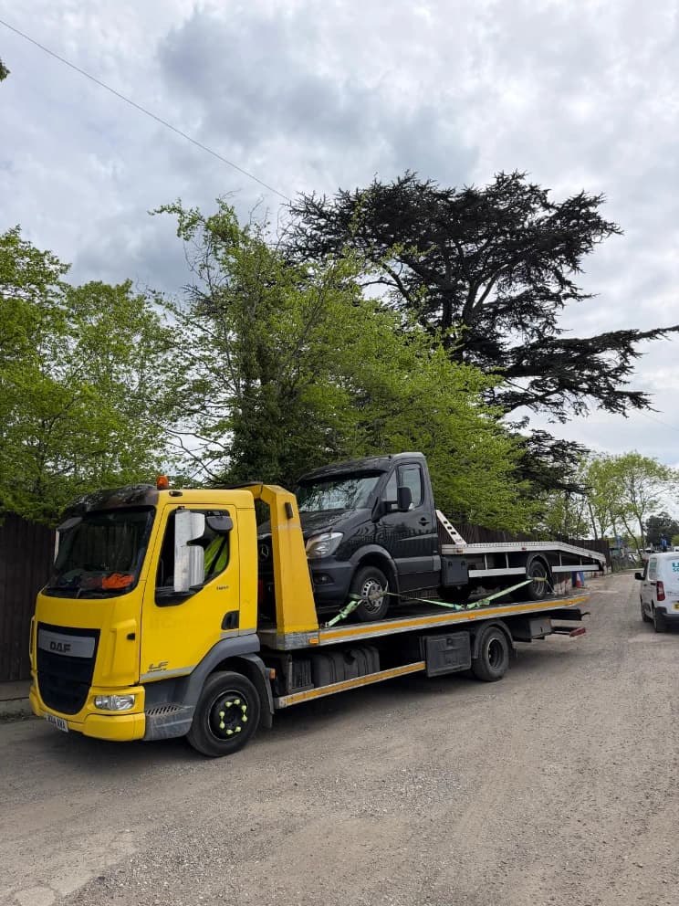 Van loaded on a flatbed recovery truck on a rural road